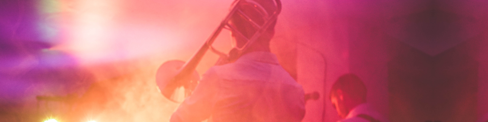 Tunnelmallinen punasävyinen kuva trumpetinsoittajan takaa