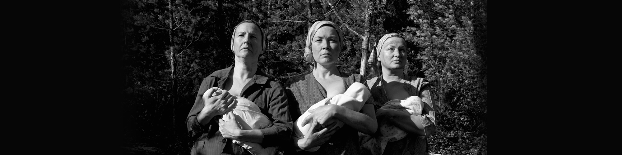 Mustavalkoinen kuva, jossa kolme naista pitävät vauvoja sylissään.